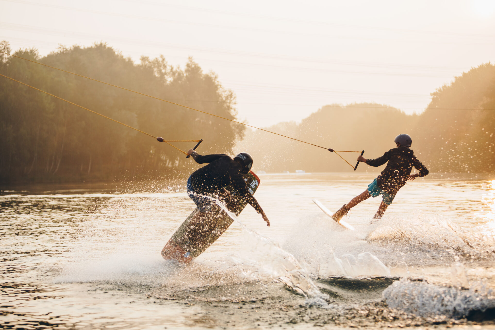 Zwei Jungen fahren Doppelleine mit dem Wakeboard und machen Tricks