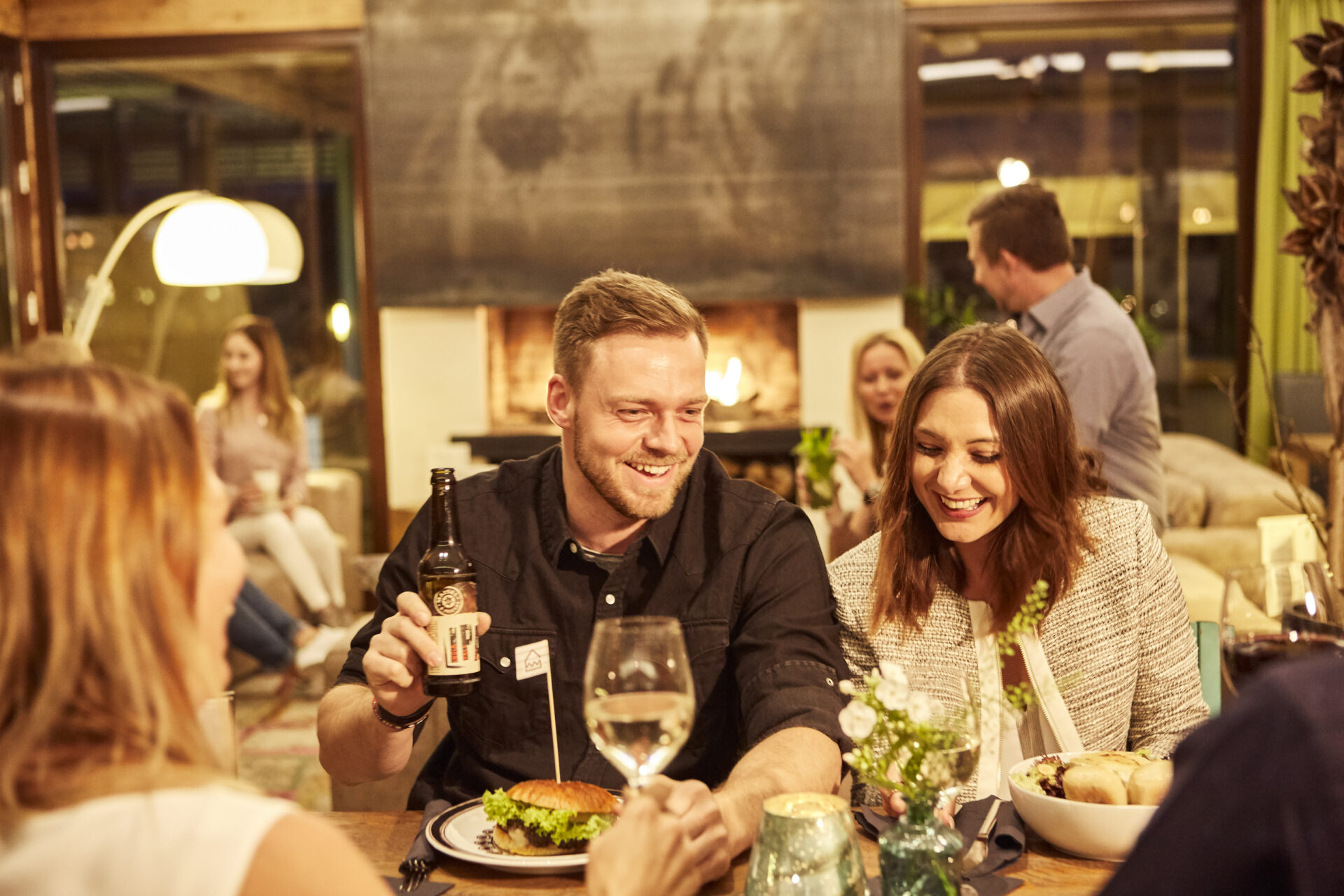 Mann und Frau sitzen im Seehaus an einem gedeckten Tisch und lachen