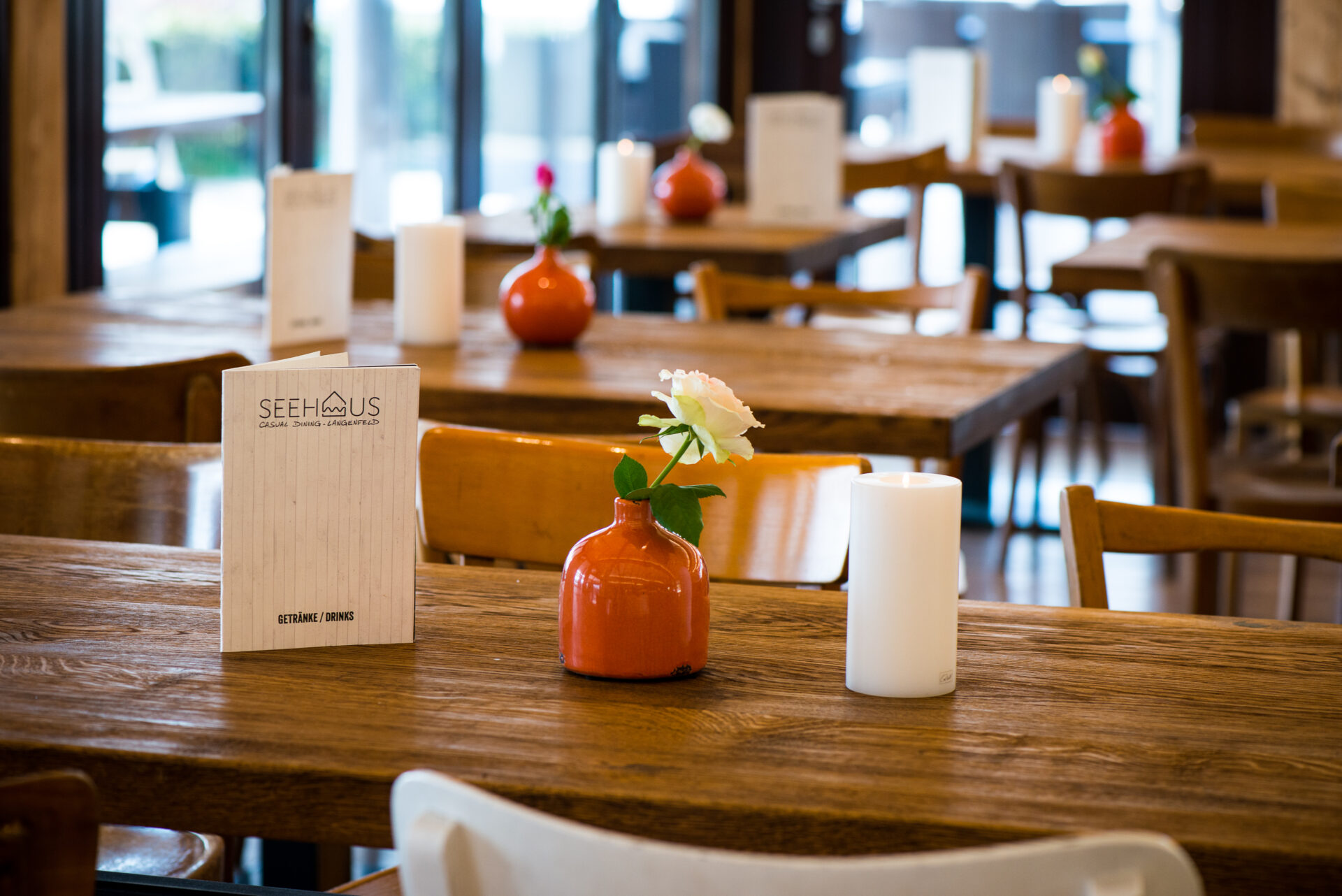 Blick auf einen Tisch im Seehaus Langenfeld mit Speisekarte, Teelicht und Blumenvase.