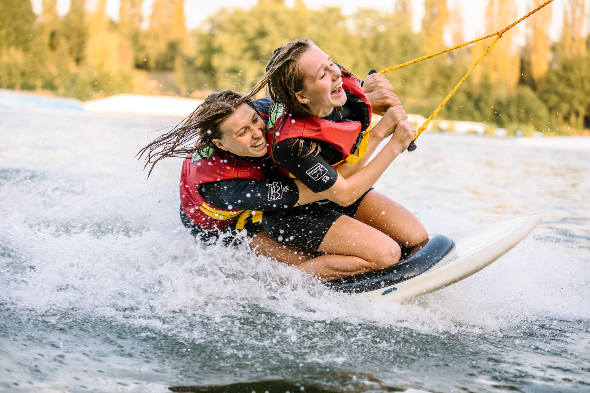 wasserski-langenfeld-kneeboard-mädchen Zwei Mädchen fahren zusammen auf einem Kneeboard und haben sichtlich Spaß