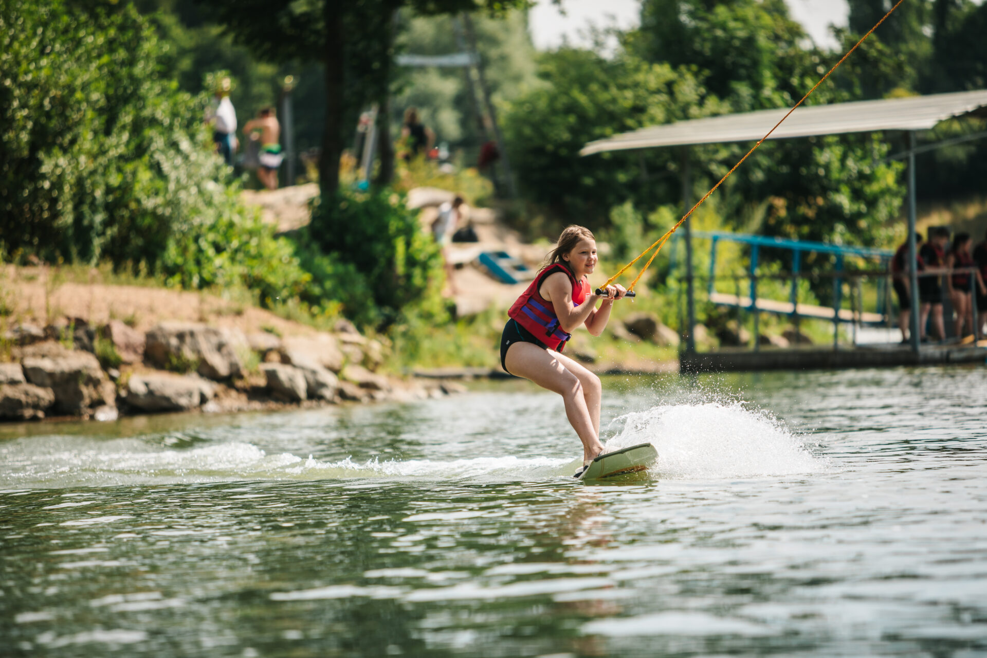 Anfängermädchen fährt mit dem Anfängerwakeboard auf der Minibahn