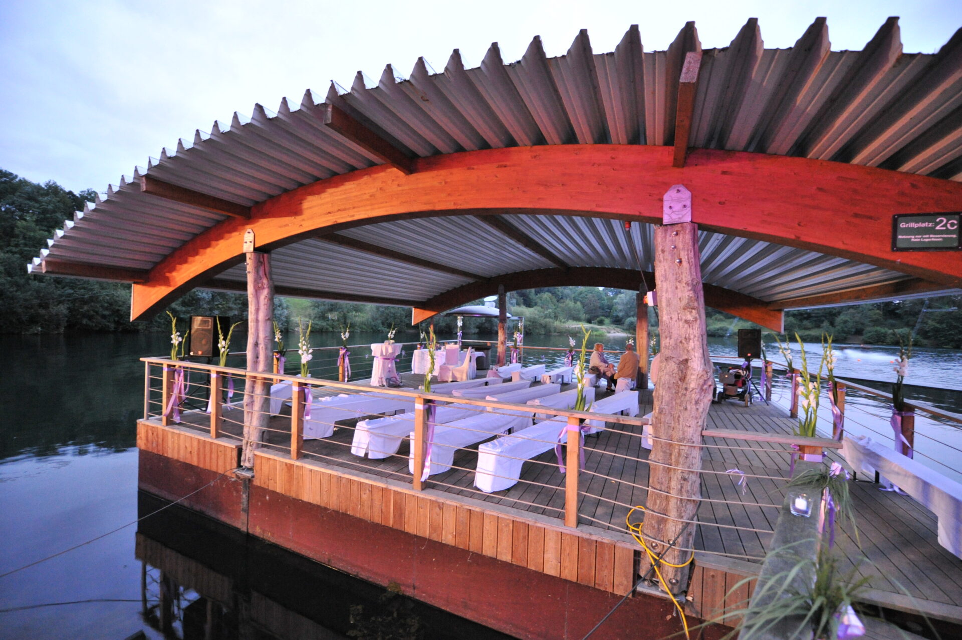 Schwimmender Grillplatz eingedeckt für eine Hochzeit, mit weißen Hussen und Blumen