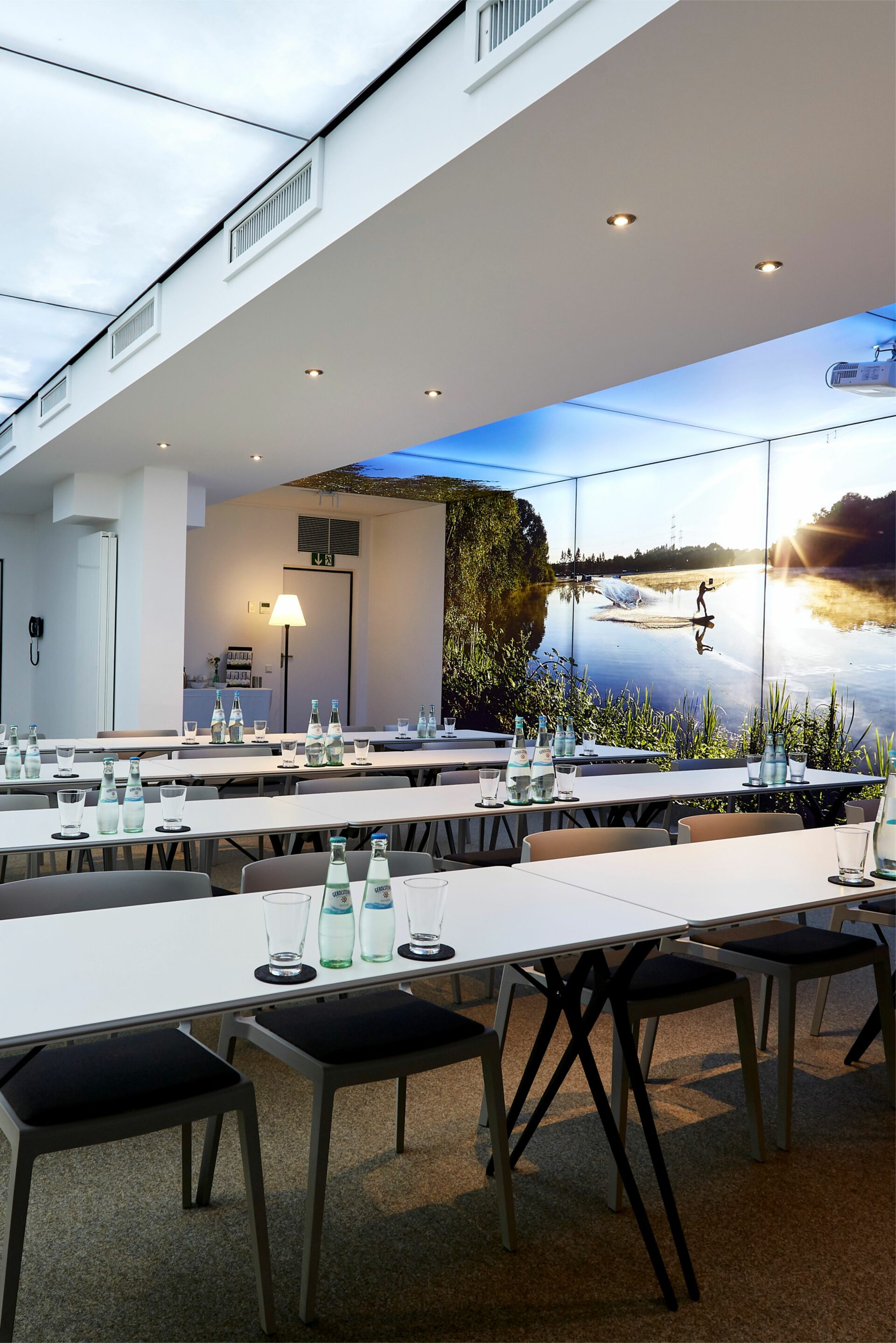 seehaus-langenfeld-tagungsraum-parlamentarisch-eingedeckt Tagungsraum mit parlamentarischer Bestuhlung inklusive Wasserflaschen auf den Tischen und dekorativen Pixlip-Wandsystemen im Hintergrund