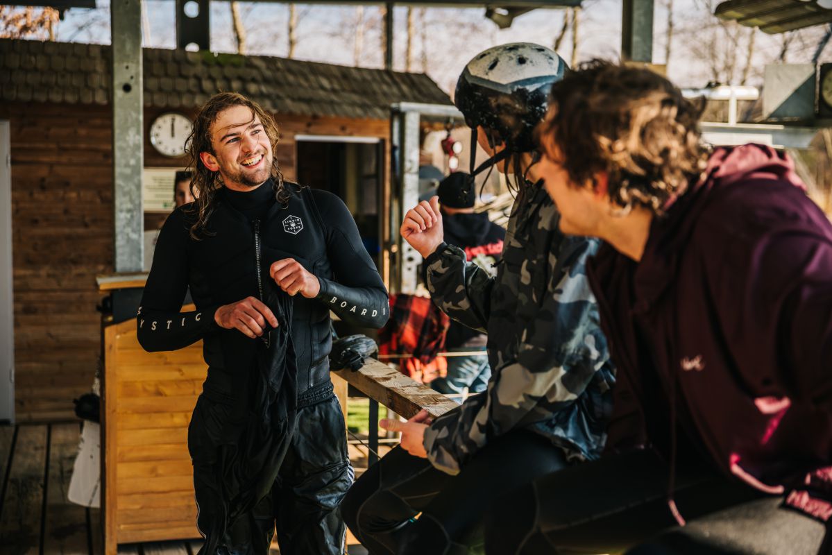 Drei Jungs in Wakeboard-Ausrüstung, die auf dem Startplatz zusammen lachen.